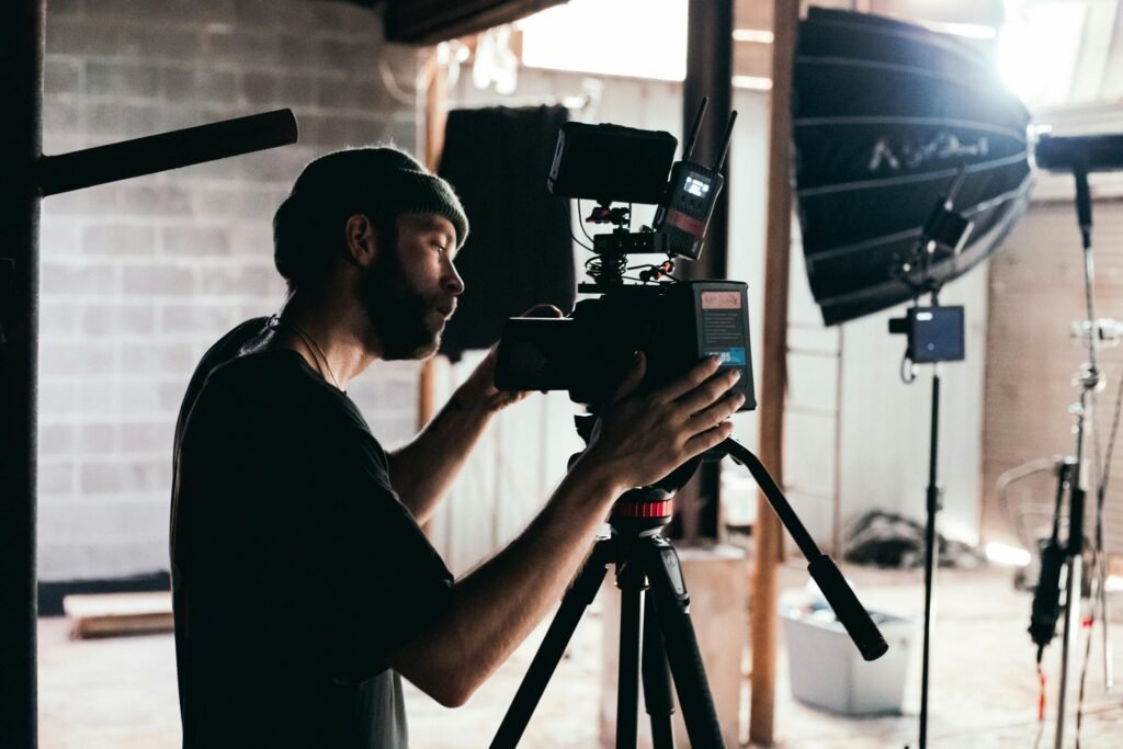 Cinematographer adjusting camera on an indoor film set with professional lighting.